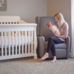 Woman in a nursery with her newborn, a newly set up nursery for her newborn baby