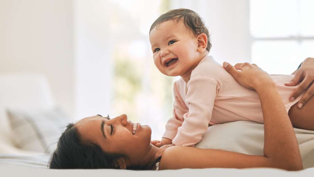 A baby on top of mom to show a fun tummy time image. While babies should sleep on their backs, they also need supervised tummy time while awake to strengthen their muscles.