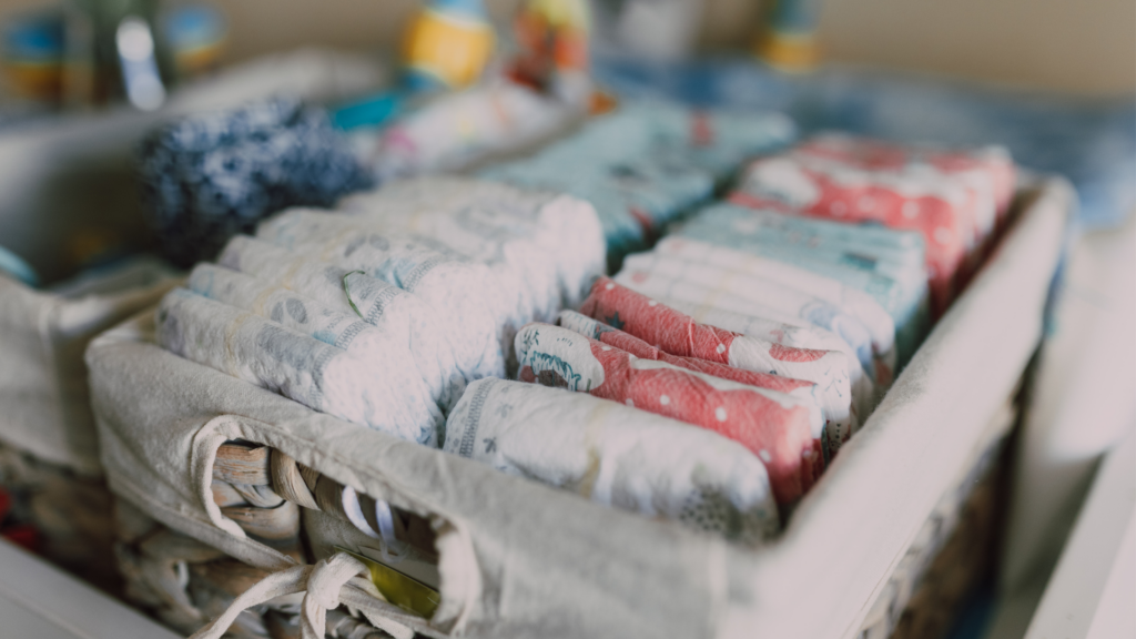 The image shows a basket of diapers and the variety of types of diapers and colors and sizes. An essential item on the Newborn Checklist